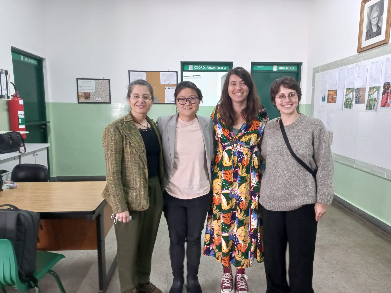 Quatro mulheres estão em pé em uma sala de escola.